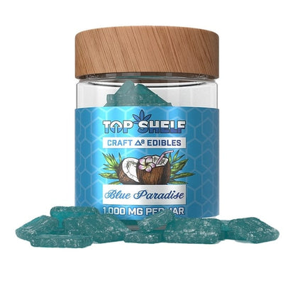 Blue Paradise Delta-8 Edibles 1000mg Jar with gummies shown spilling out from the jar, from Top Shelf Hemp Co, featuring a coconut flavor design with blue-colored gummies.